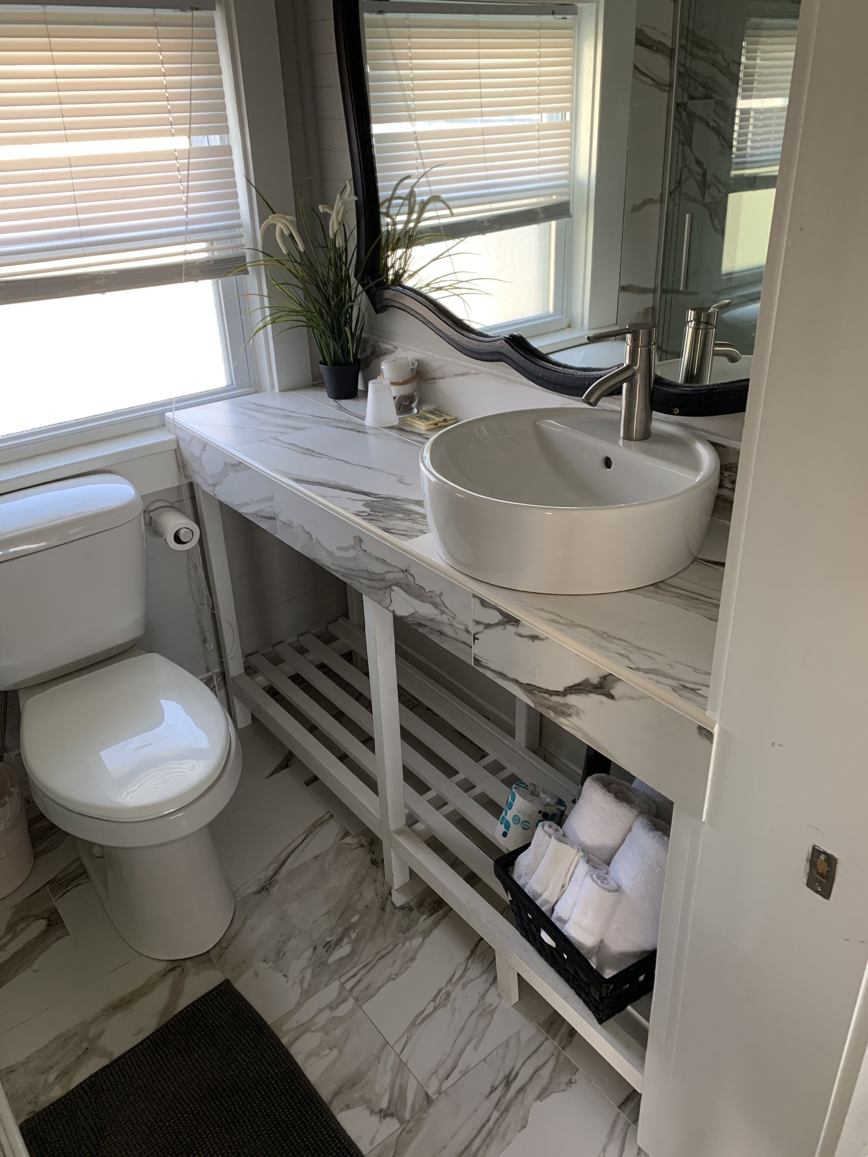 A bathroom with a white toilet, a sink with a marble countertop, and a mirror above the sink.