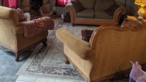 Un salon avec une cheminée en pierre, deux canapés, un téléviseur et un ventilateur de plafond.