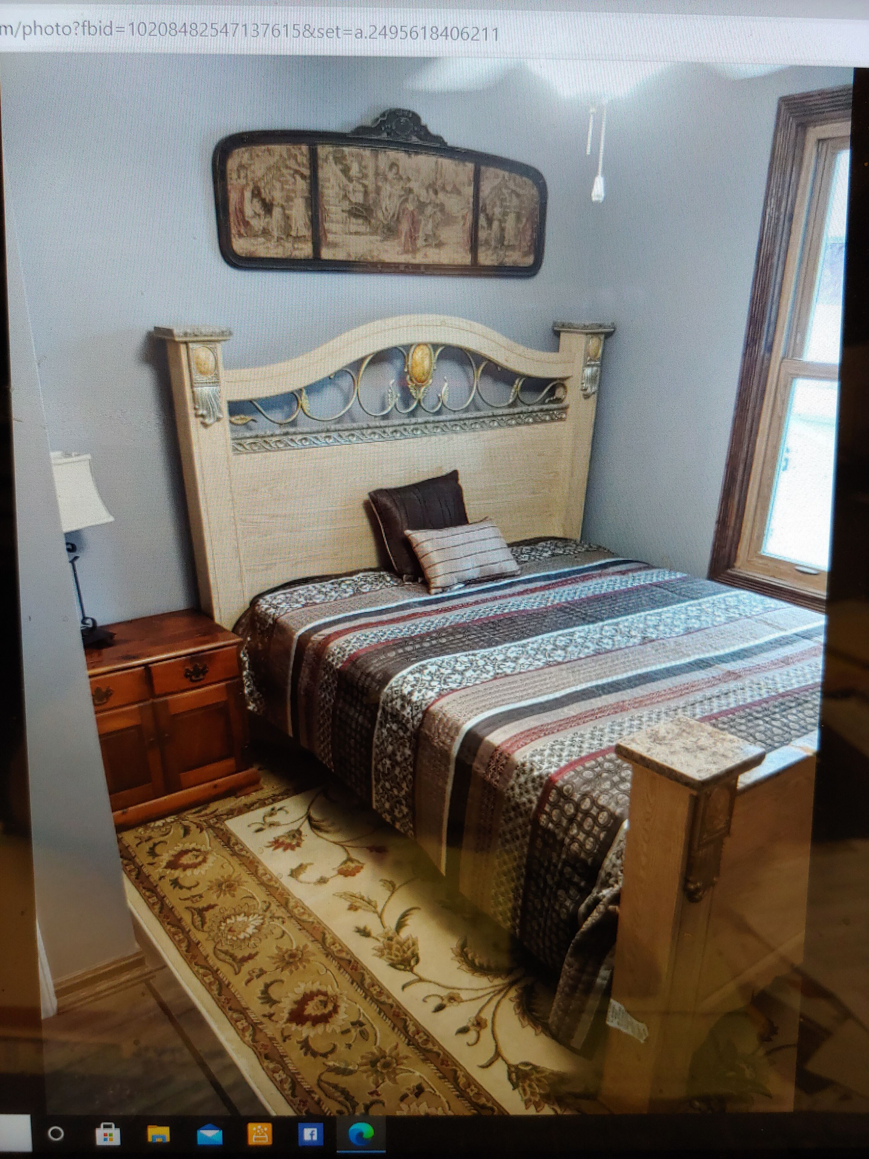 A bedroom with a bed, a nightstand, a lamp, and a framed picture on the wall.