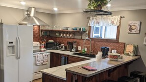 Une cuisine dotée d’un îlot central, de tabourets de bar, d’un réfrigérateur et d’une poubelle.