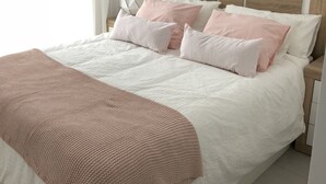 A neatly made bed with a white and pink color scheme, a wooden headboard, and a bedside table with a lamp. - Fuengirola, 1 min. walk from the beach  (Fuengirola)