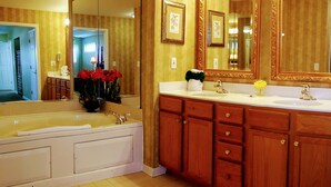 Une salle de bain dotée d’une grande baignoire, d’un meuble-lavabo en bois et de deux miroirs.