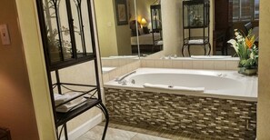 Un baño con una bañera grande, un espejo y un estante con toallas.