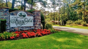 A sign for Fairfield Plantation with a stone wall and a landscaped garden with red flowers. - Fairfield Plantation Resort - Tara II Two Bedroom Deluxe (Villa Rica)