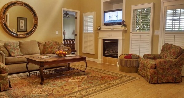 Una sala de estar con sofá, sillón, mesa de centro y chimenea.