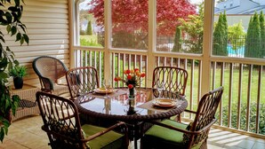 A covered patio with a glass table surrounded by wicker chairs, a vase of flowers, and a view of a fenced yard with trees. - Fairfield Plantation Resort - Tara II Two Bedroom Deluxe (Villa Rica)