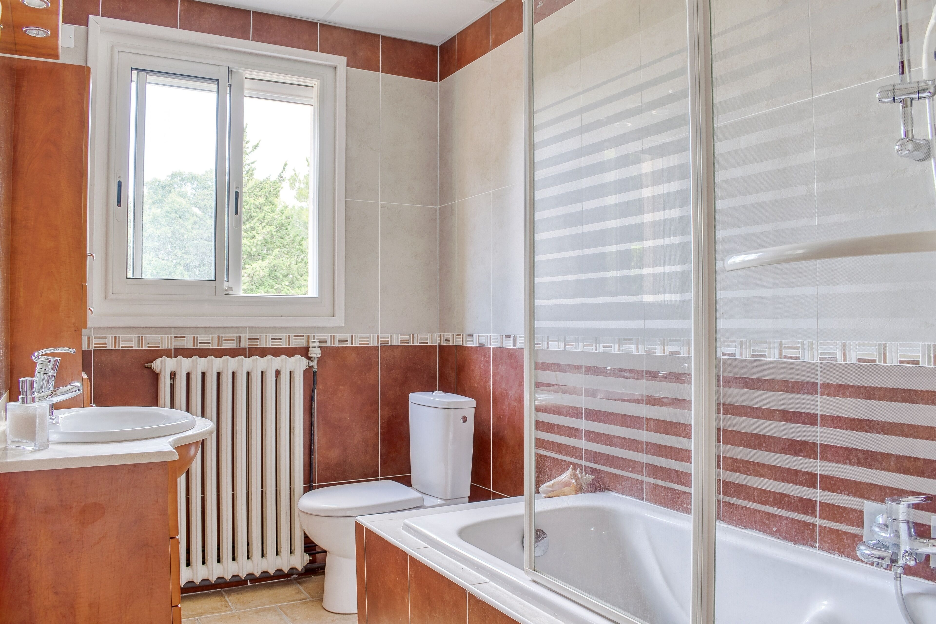 Une salle de bain avec une fenêtre, un lavabo, des toilettes et une baignoire.