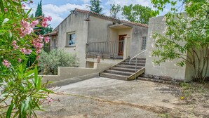 Una casa de dos pisos con fachada de concreto, una puerta de madera y una escalera de metal que da al piso superior.
