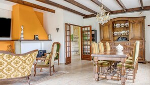 Comedor con mesa y sillas de madera, araña y aparador con vajilla.