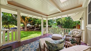 Varanda coberta com vista para um jardim exuberante e uma árvore.