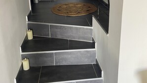A staircase with dark tiles leading to a door with a decorative metal railing. - Ground floor apartment, T2 type, sea view. (Santa-Reparata-Di-Balagna)