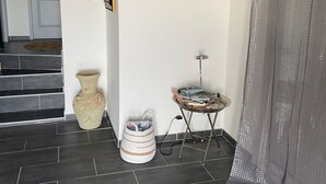 A room with a tiled floor, a small table with magazines, a vase, and a bag. - Ground floor apartment, T2 type, sea view. (Santa-Reparata-Di-Balagna)