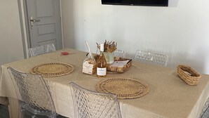 A dining area with a table set for four, clear chairs, a woven placemat, a bottle of wine, and a basket. - Ground floor apartment, T2 type, sea view. (Santa-Reparata-Di-Balagna)