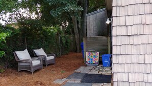 Eine Terrasse mit Korbstühlen, einem bunten Handtuchhalter und einer blauen Recyclingtonne.