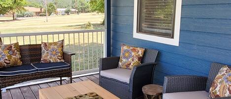A covered porch with wicker furniture and a wooden table.