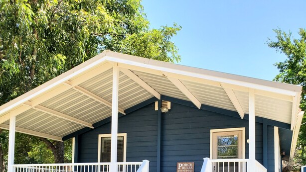 A small building with a porch, a staircase leading up to the entrance, and a signboard with text. - Lakeview Cottage Near Boat Ramp (Burnet)