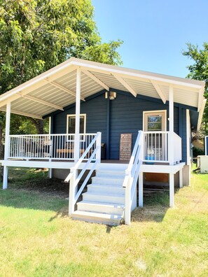 A small building with a porch, a staircase leading up to the entrance, and a signboard with text. - Lakeview Cottage Near Boat Ramp (Burnet)