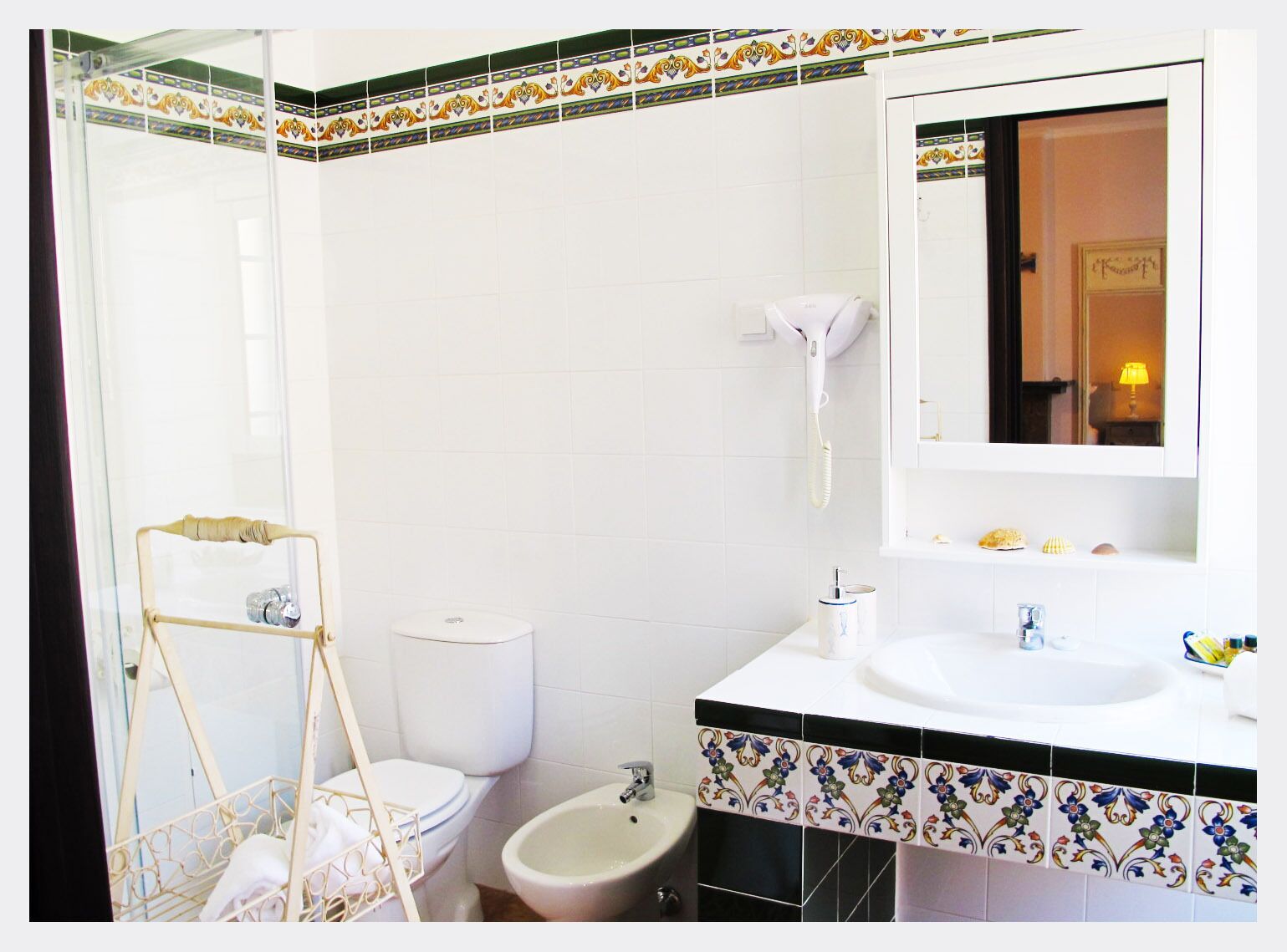 A bathroom with a toilet, bidet, and a sink with a mirror.