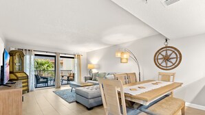 A spacious living area with a dining table, sofas, and a TV.