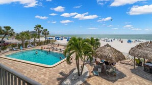 A pool area with lounge chairs, palm trees, and a beach view.