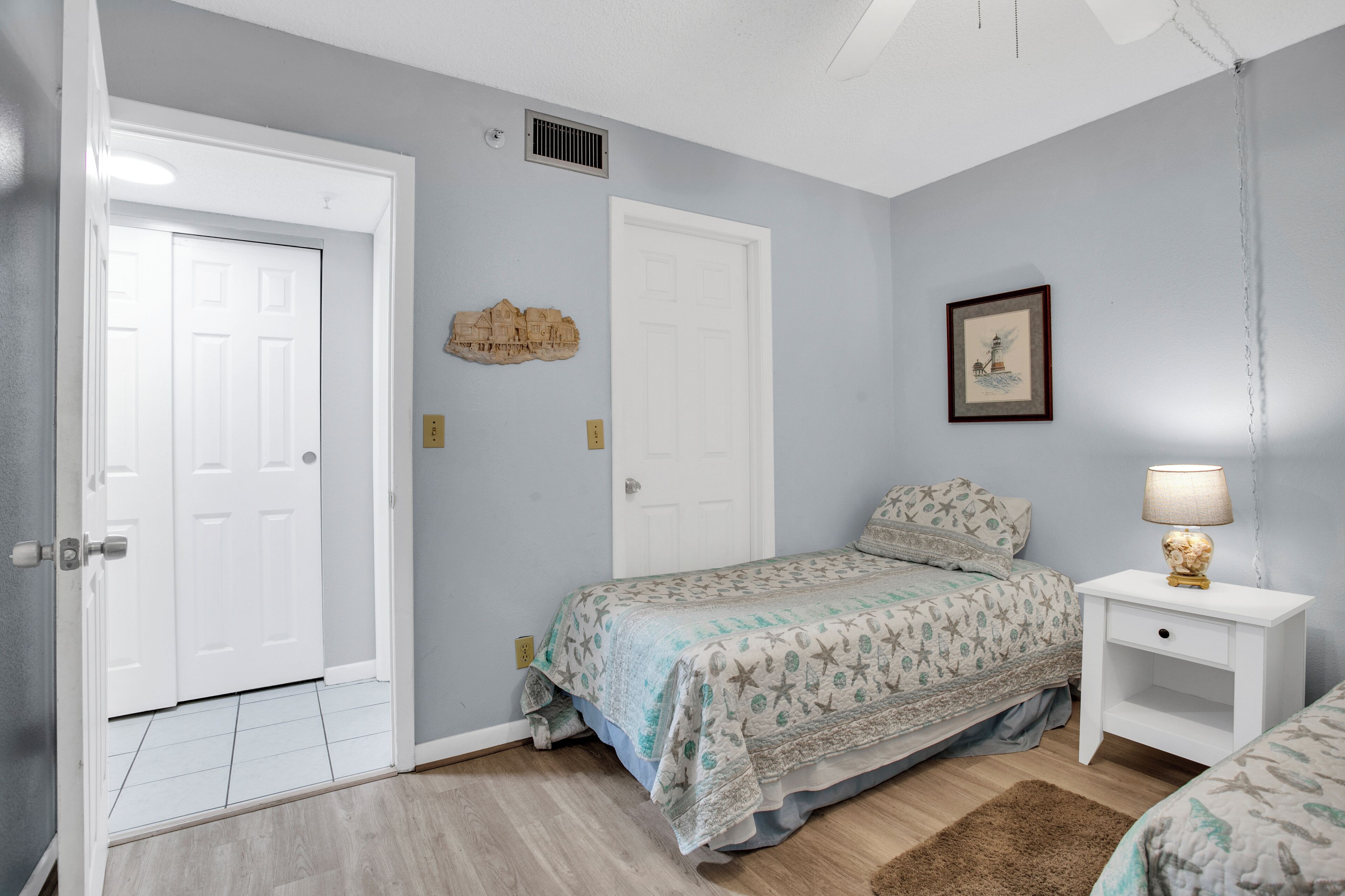 A bedroom with a bed, a nightstand, a lamp, and a door.