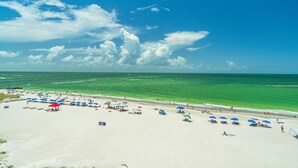 Una playa de arena blanca, agua turquesa cristalina y algunas sombrillas.
