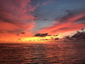 A sunset over the ocean with a clear sky and calm waters.