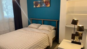 A bedroom with a bed, a nightstand, a lamp, and a wall-mounted shelf with decorative items. - Cosy accommodation near Paris and Disneyland (Villiers-sur-Marne)