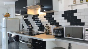 A modern kitchen with black and white tiles, stainless steel appliances, and a white refrigerator. - Cosy accommodation near Paris and Disneyland (Villiers-sur-Marne)