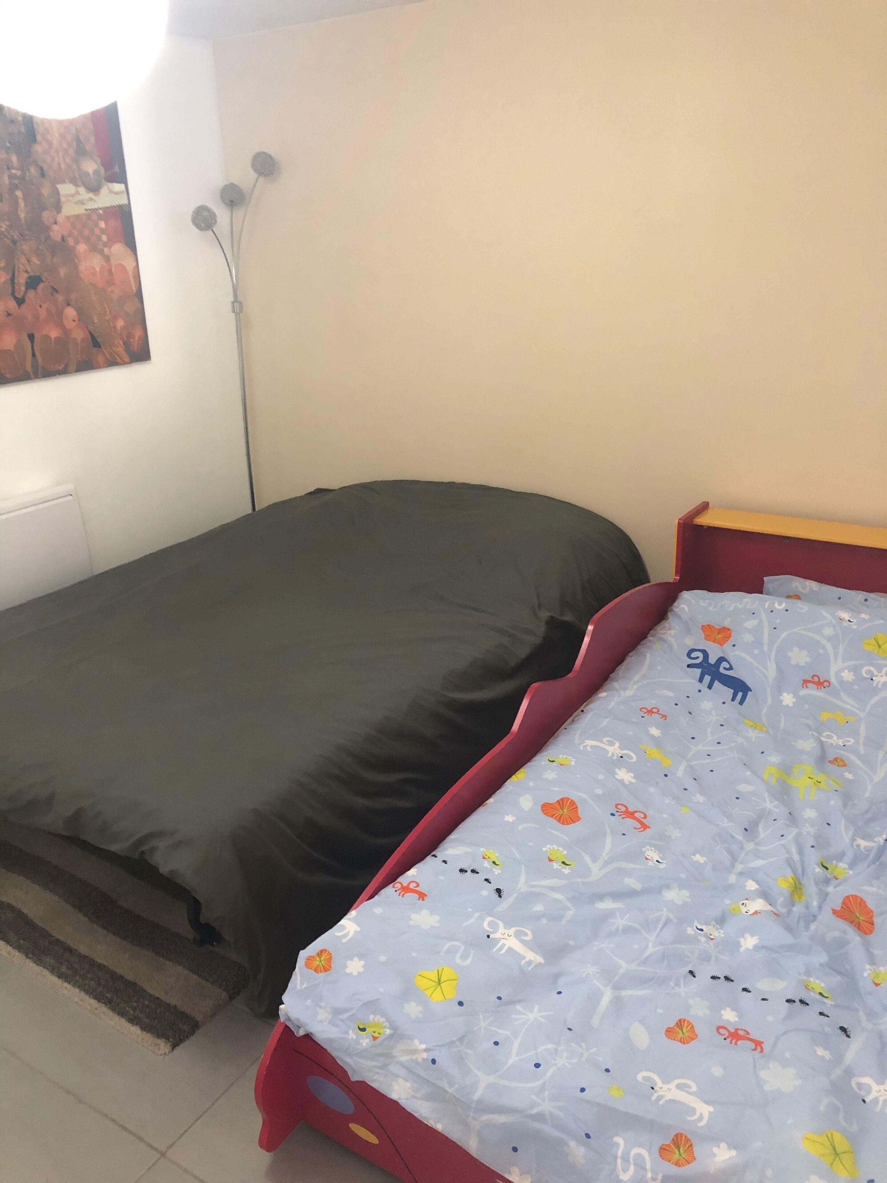 Una camera da letto con un letto singolo, un comodino e una lampada fissata al muro.
