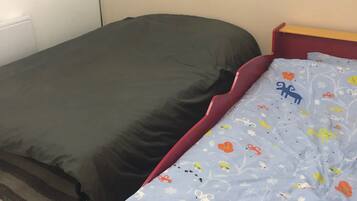 Una camera da letto con un letto singolo, un comodino e una lampada fissata al muro.