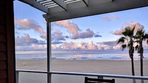 Vista sulla spiaggia da un balcone coperto con una panchina e una statua.