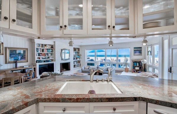 Relax in this inviting living area with a fireplace, comfortable seating, and stunning beach views.