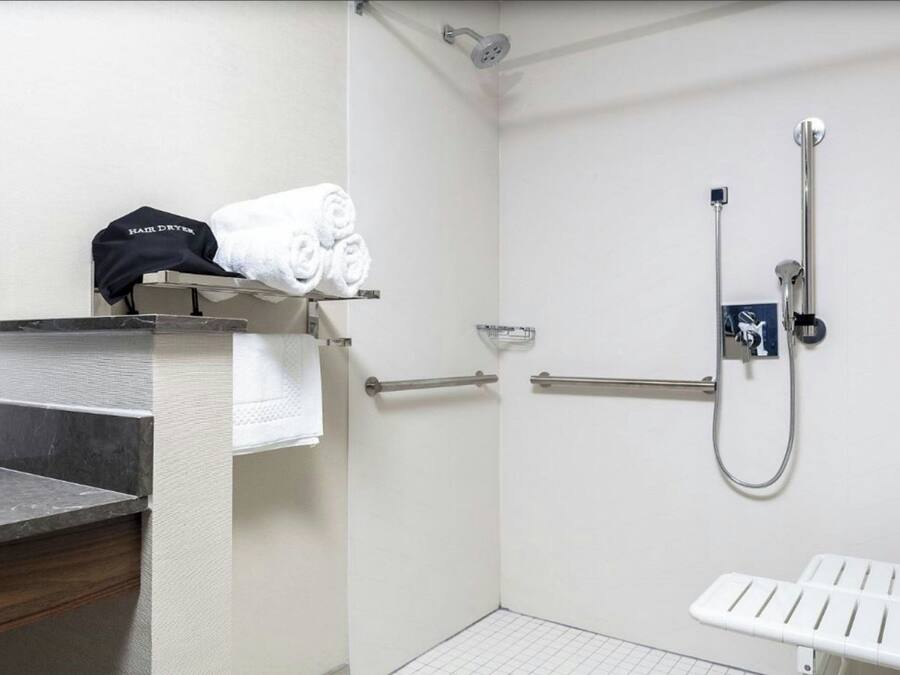 A bathroom with a shower, a towel rack, a sink, and a toilet.