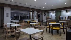 A restaurant with wooden tables and chairs, a bar area, and a clock on the wall. - Fairfield Inn & Suites by Marriott Monahans (Monahans)
