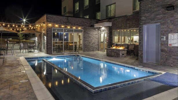 An outdoor swimming pool with stone walls and a fire feature, surrounded by outdoor seating and string lights. - Fairfield Inn & Suites by Marriott Monahans (Monahans)
