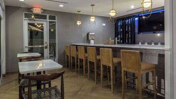 A modern bar area with a counter, bar stools, and pendant lighting.