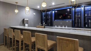 A bar area with a long counter, multiple bar stools, and a display of glassware. - Fairfield Inn & Suites by Marriott Monahans (Monahans)