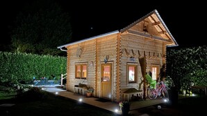 A log cabin with a wooden exterior, a porch with seating, and a bicycle parked outside.