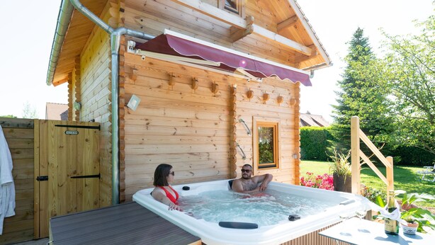 A wooden cabin with a hot tub and a covered patio area.