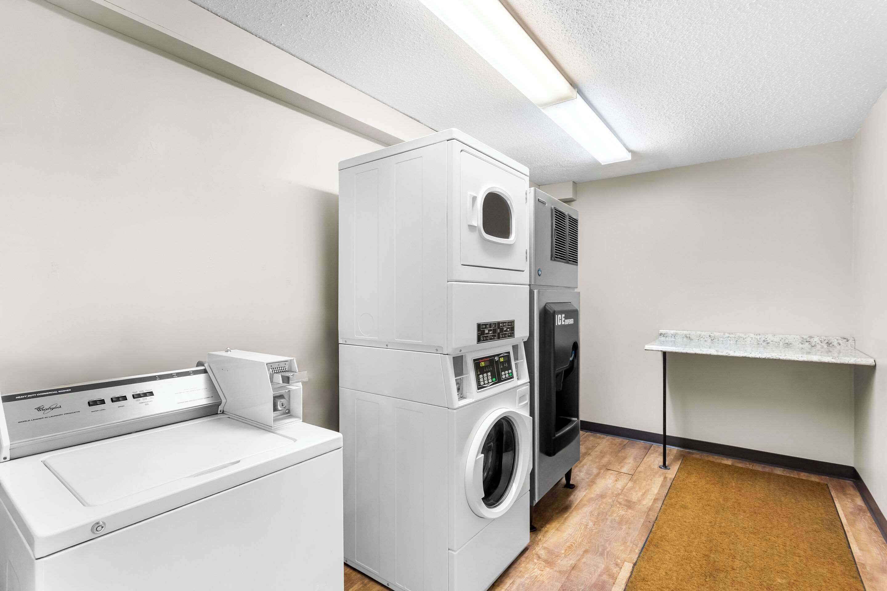 A laundry room with a front-loading washer and dryer, a small table, and a bench.