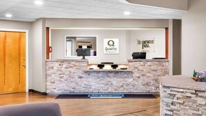 A reception desk with a stone facade, a sign reading "Quality by Choice Hotels," and a "DEWAY INN" sign. - Rodeway Inn Gorham Riverside (Gorham)
