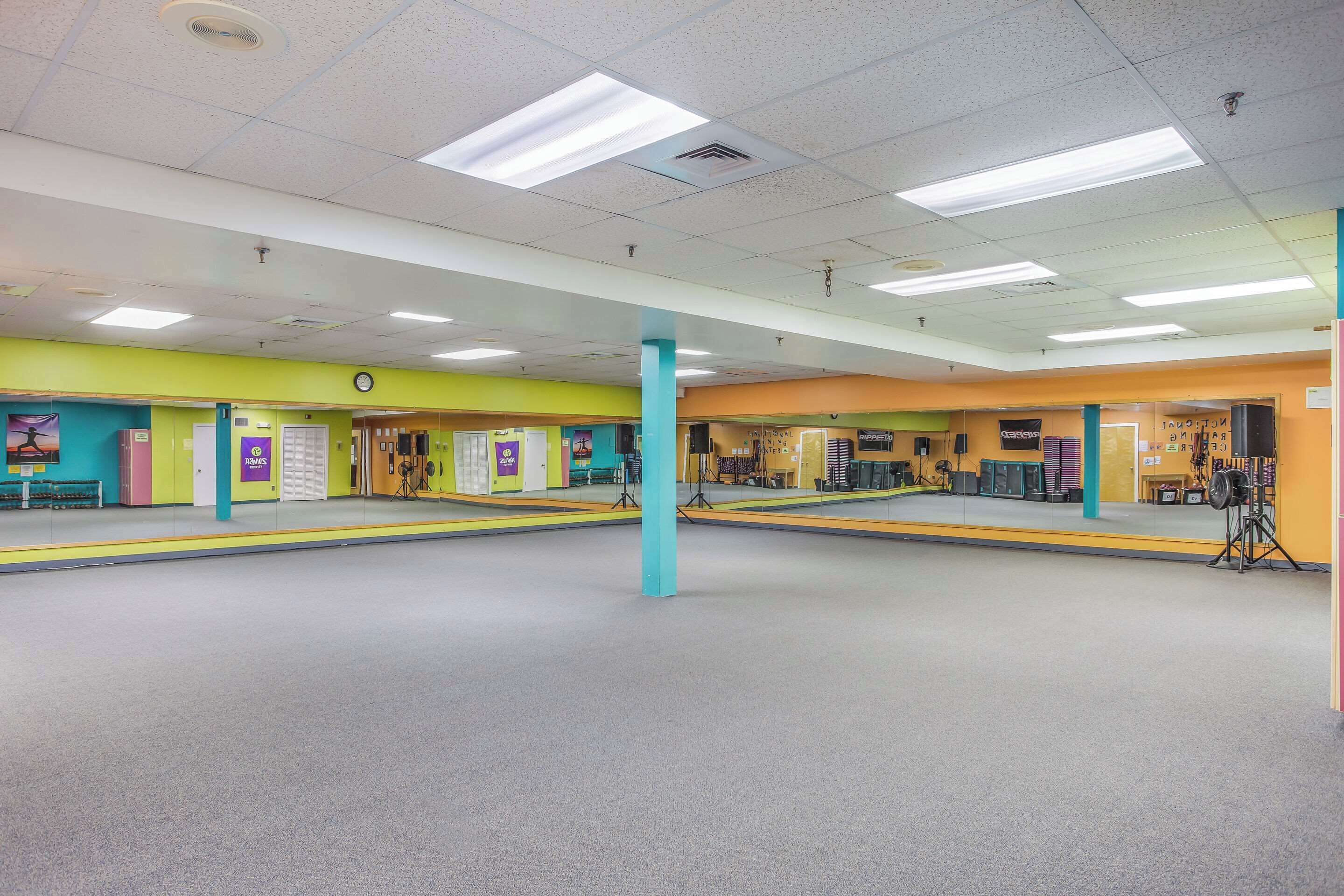 A spacious indoor area with a high ceiling, fluorescent lighting, and a central pillar.