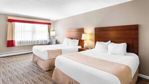 A hotel room with two beds, a large window with curtains, a nightstand with a lamp, and a carpeted floor. - Rodeway Inn Gorham Riverside (Gorham)
