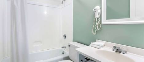 Une salle de bain avec une baignoire, des toilettes et un lavabo avec un miroir au-dessus.