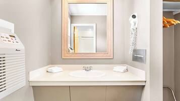 A modern bathroom with a large mirror, a sink, and a hairdryer mounted on the wall.