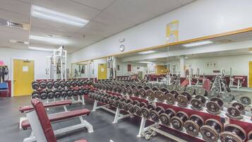 Uma academia com equipamentos de musculação e bancos.
