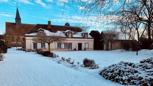 A snow-covered courtyard with a building featuring a tower and multiple windows.