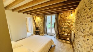 A bedroom with a bed, a chair, and a stone wall.