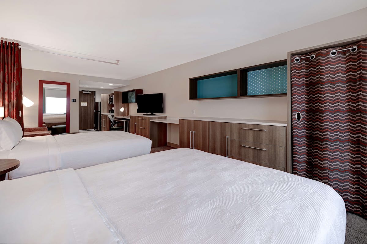 Een hotelkamer met twee bedden, een televisie, een bureau en een spiegel.